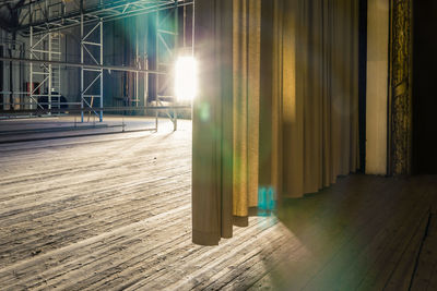 Sunlight streaming over an abandoned theatre stage with an open curtain