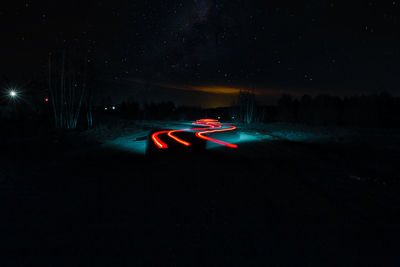 Light trails on road against sky at night