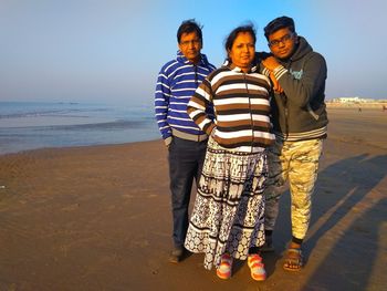 Friends standing at beach against sky