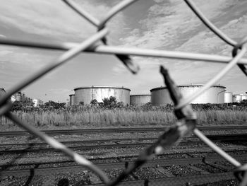 Railroad tracks against sky seen through chainlink fence