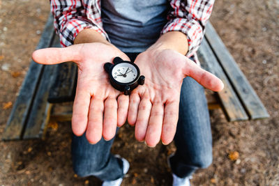 Midsection of person holding clock