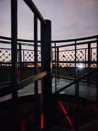 Railing by building against sky at dusk