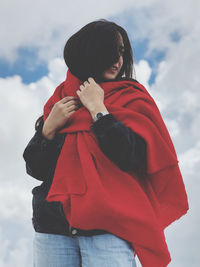 Midsection of woman with red umbrella standing against sky