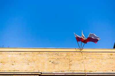 Low angle view of flag on building against blue sky