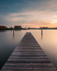 Pier over lake against sky during sunrise