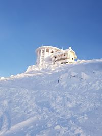 Low angle view of snowcapped mountain against clear blue sky