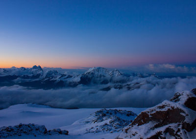 Scenic view of snowcapped mountains against sky at sunset