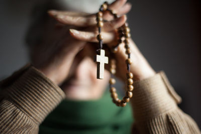 Close-up of hand holding cross against blurred background