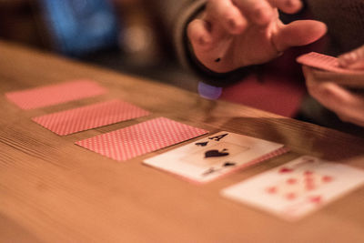 Close-up of hands holding playing cards on table