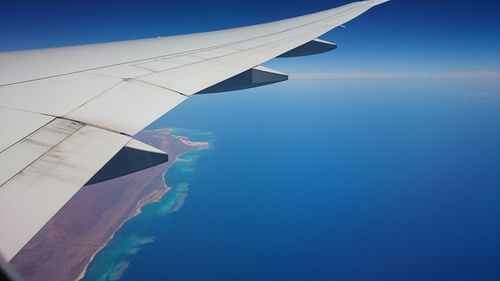 Close-up of airplane flying over sea against blue sky