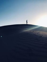 Silhouette man standing on shore against clear sky