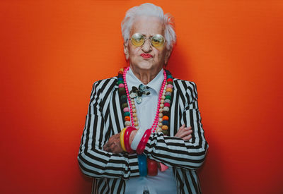 Portrait of serious senior woman standing against red background