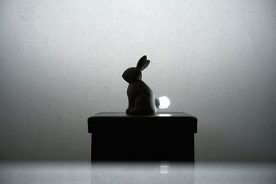 Close-up of toy statue on table against wall