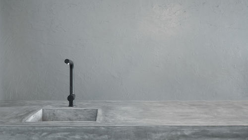 Faucet against white wall in empty kitchen