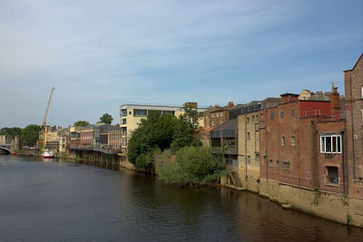 Buildings by river against sky in city