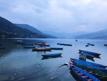 Boats moored at harbor against sky