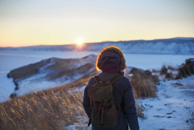 Portrait of young woman standing on snow during sunset