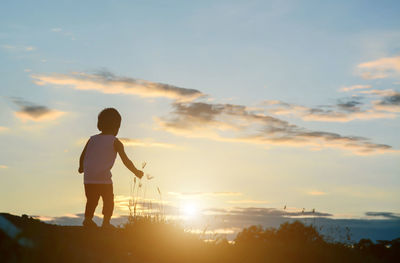 Rear view of silhouette man standing against sky during sunset