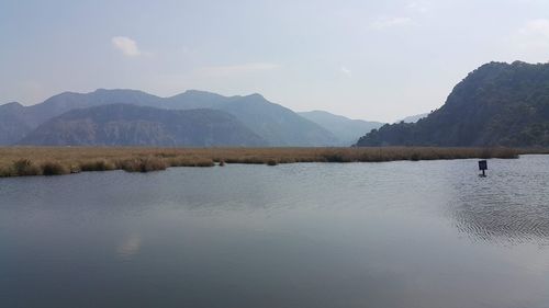 Scenic view of lake by mountains against sky