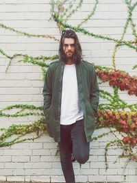 Portrait of young man standing against ivy