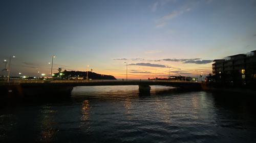 Bridge over river against sky at sunset