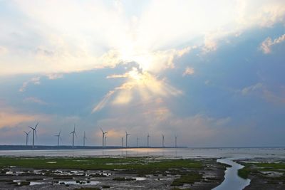 Traditional windmill by sea against sky