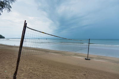 Volleyball net at sea shore against sky