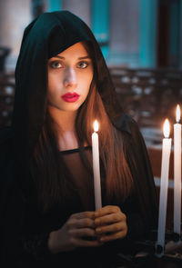 Portrait of beautiful young woman holding candle
