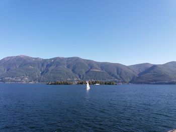 Scenic view of lake and mountains against clear blue sky