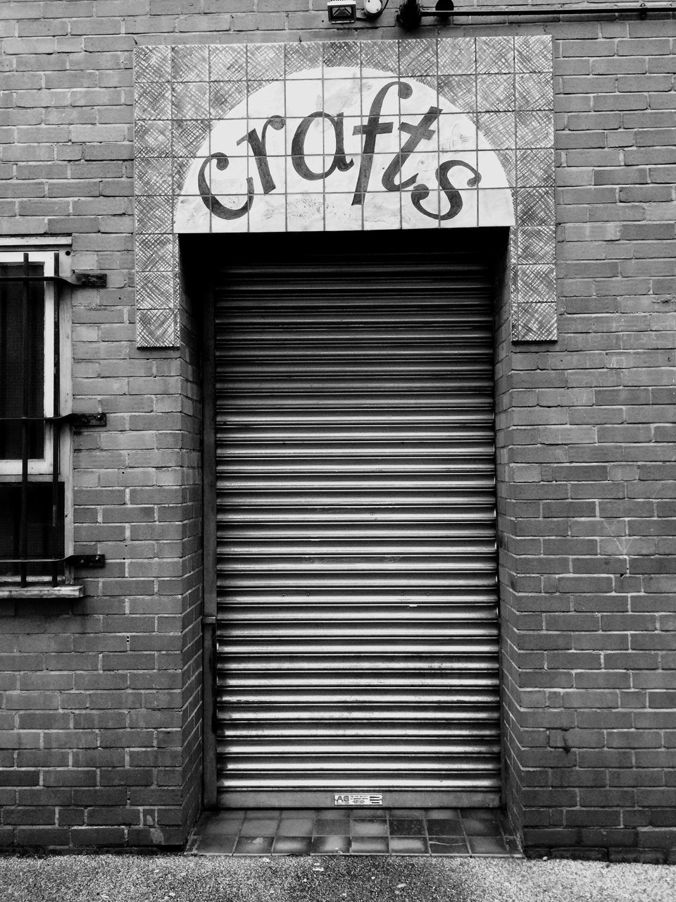 building exterior, architecture, built structure, brick wall, text, wall - building feature, closed, western script, communication, wall, door, window, outdoors, graffiti, shutter, day, house, sidewalk, no people, entrance