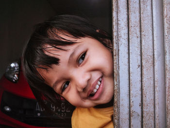 Portrait of a smiling girl looking through window