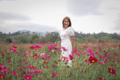 Rear view of woman standing on field against sky