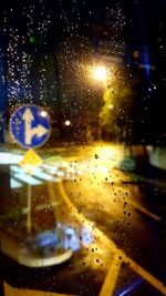 Close-up of wet window against sky at night