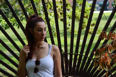 Young redhead woman standing against metal fence