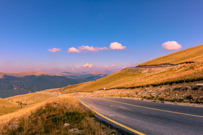 Road by mountains against blue sky