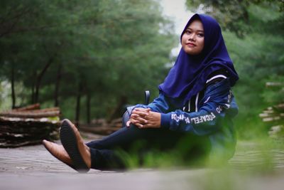 Young woman looking away while sitting outdoors