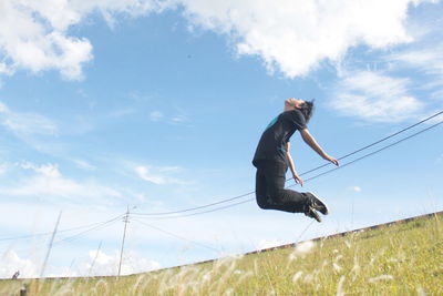 Man jumping on field against sky