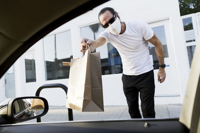 Man delivers bag to car window