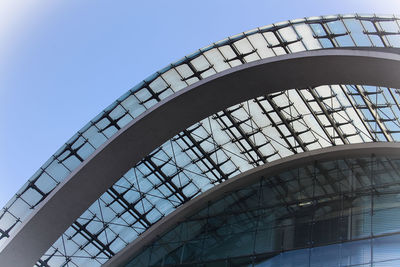 Low angle view of glass building against clear blue sky