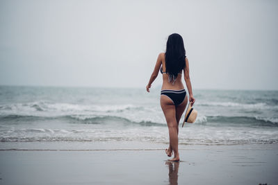 Woman standing at beach against sky