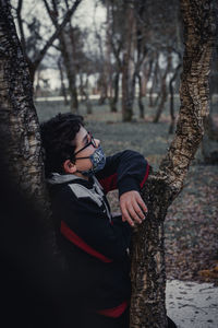 Midsection of woman standing by tree trunk in forest