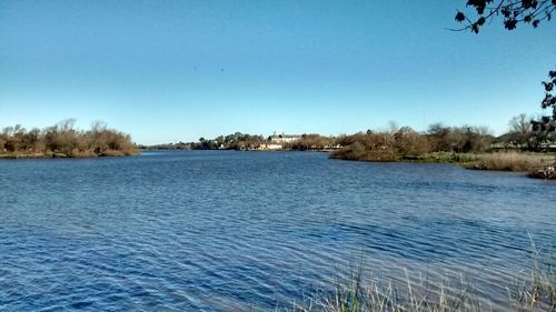 Scenic view of lake against clear blue sky