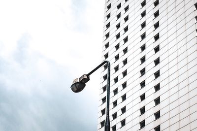 Low angle view of street light by building against sky