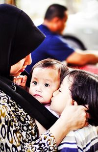 Close-up of mother embracing daughters