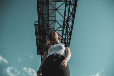 Low angle view of young woman standing against sky