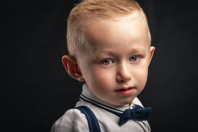 Close-up portrait of cute boy against black background