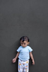 Portrait of cute boy standing against wall