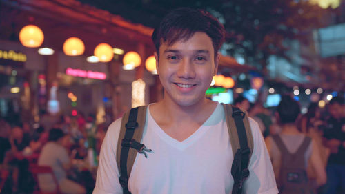 Portrait of smiling young man in city at night