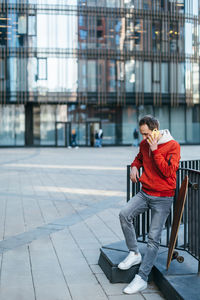 Attractive male in red jacket calling by the cell phone. urban and street photo. 