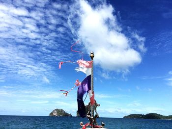 Torn flag by sea against sky